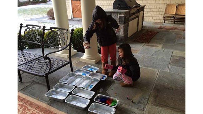 The girls begin filling the food trays with colored water. Once frozen, these become the building blocks for the igloo. (Image: The Shyong and Trokhan Families)
