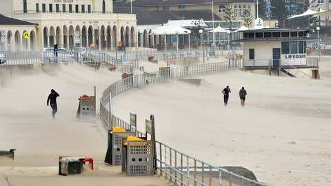 Joggers struggle against sand whipped up by strong winds at Bondi Beach in Sydney on April 21, 2015. Sydney and surrounding areas were lashed by wild weather with trees felled, thousands of homes without power, schools shut and huge sea swells that hampered cruise ship movements.  (Peter Parks/AFP/Getty Images)