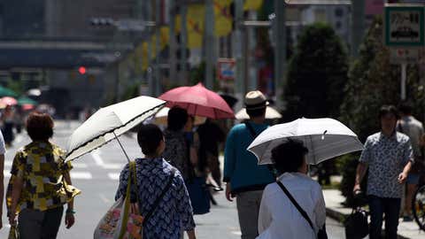 Pedestrians walk on the street under the sun at the Ginza shopping district in Tokyo on July 19, 2015. (Toshifumi Kitamura/AFP/Getty Images)