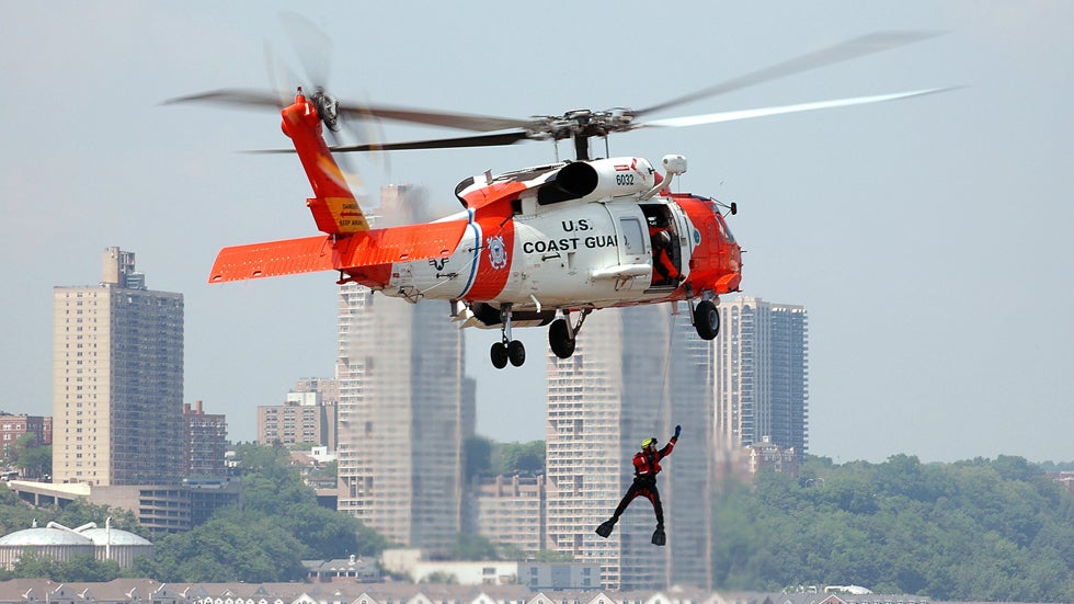 In this image provided by the U.S. Coast Guard, a Coast Guard rescue swimmer hangs from a HH-60 Jayhawk helicopter, from Air Station Cape Cod, while performing a search and rescue demonstration for people enjoying Fleet Week festivities May 27, 2006 in New York City. (Matthew Belson/U.S. Coast Guard via Getty Images)