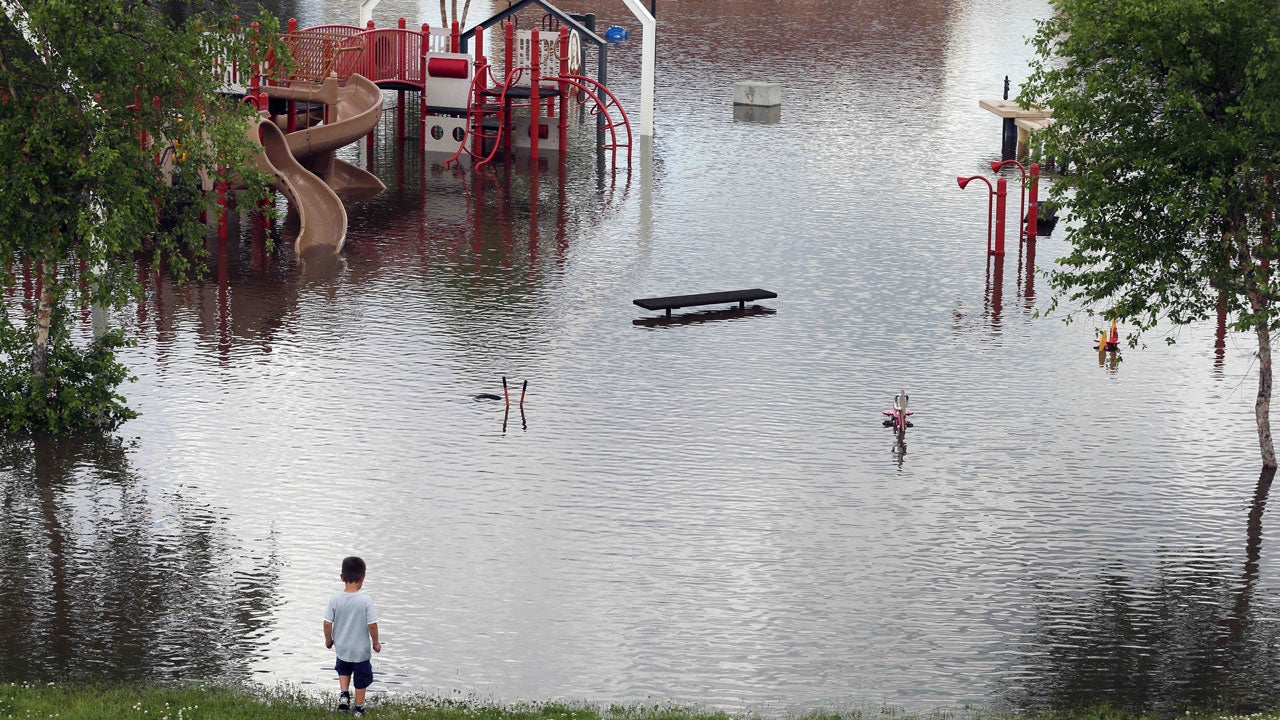 A young boy checks out the water covering the playground at Harriet Island where the Mississippi River continued to rise, Tuesday, June 24, 2014, in St. Paul, Minnesota. (AP Photo/Jim Mone)
