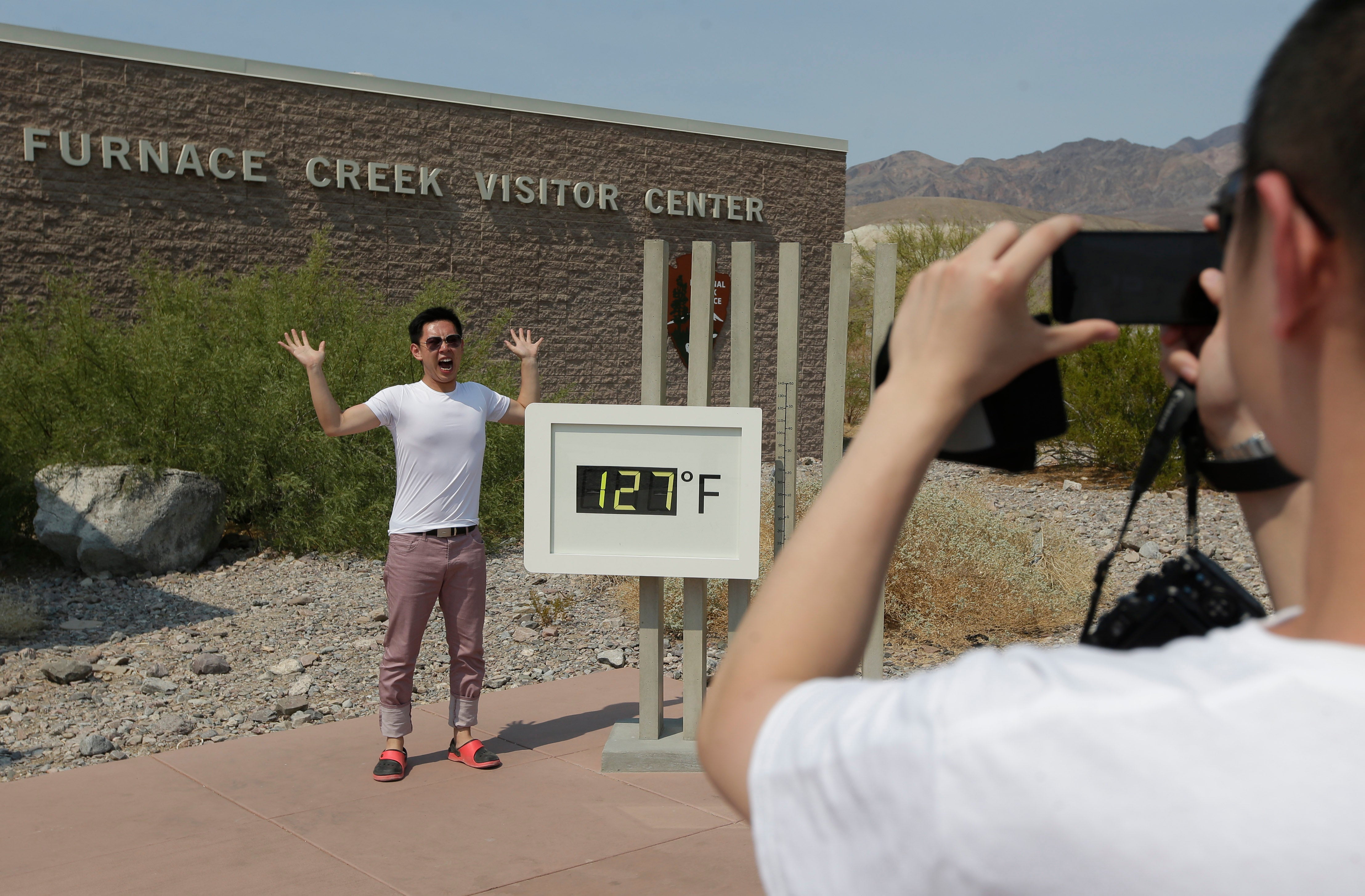 Cheng Jia, of China, takes a picture of Yongxin Yan by a digital thermometer at the Furnace Creek Visitor Center in Death Valley National Park Friday, June 28, 2013 in Furnace Creek, Calif. (AP Photo/Chris Carlson)