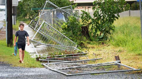 A boy walks past a fence brought down by Tropical Cyclone Marcia along the road into the northern Queensland town of Yeppoon on February 20, 2015. (PETER PARKS/AFP/Getty Images)