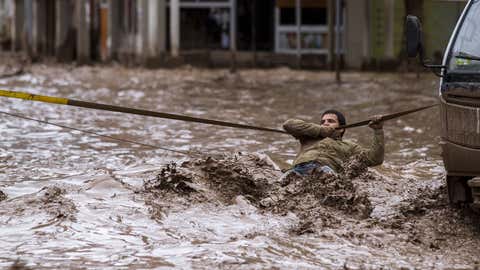 A man clings to a security line to cross a street flooded by the overflowing of the Copiapo River due to heavy rainfall that affected some areas in the city, in Copiapo, Chile on March 26, 2015. (STR/AFP/Getty Images)