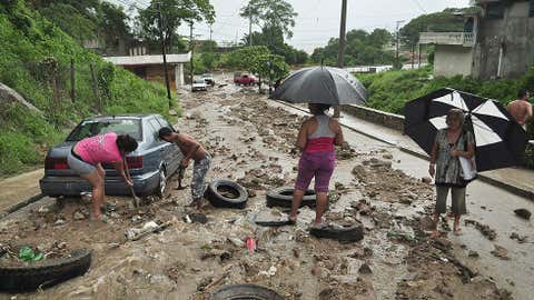 A couple tries to remove their car from a swampy street in Acapulco, Guerrero state, Mexico, after heavy rains hit the area on September 15, 2013.  (Image: Claudio Vargas/AFP/Getty Images)