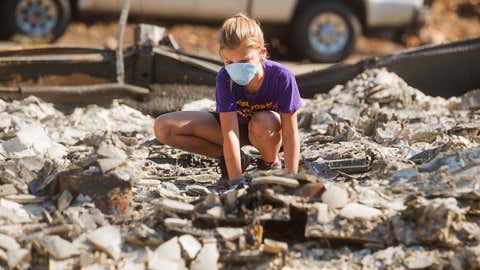 Mia Hoogendoorn searches through her grandparent's home, which was destroyed by a wildfire, near Middletown, Calif., Sept. 21, 2015. (AP Photo/Noah Berger)