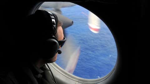 In this photo taken from the Royal New Zealand Air Force P-3K2-Orion aircraft, a spotter looks out of a window in search of debris from the missing Malaysia Airlines Flight 370, in the Indian Ocean off the coast of western Australia on Sunday, April 13, 2014. (AP Photo/Greg Wood, Pool)