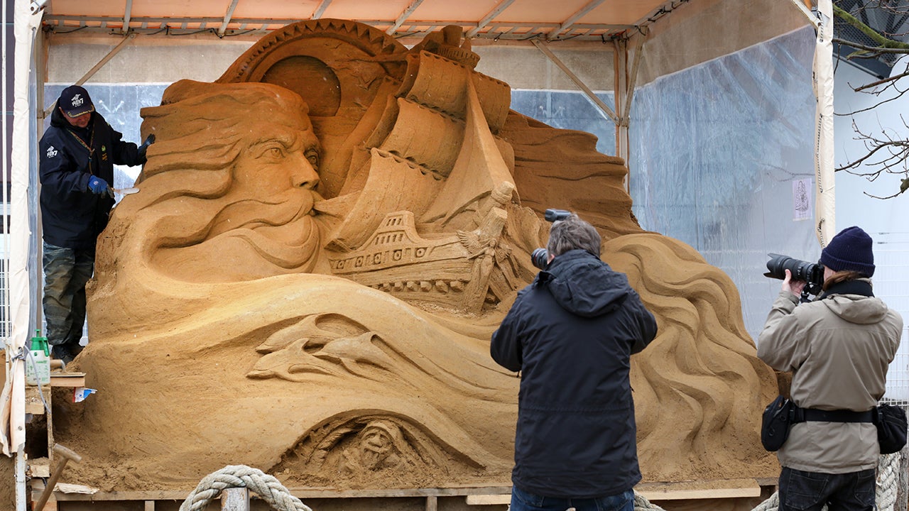 Sergey Tselebrovsky from Russia works on his sand sculpture "The Vikings" as photographers take pictures at a bathing area of the Baltic Sea in Warnemuende, Germany, on April 5, 2013. Nine artists from six countries design sand sculptures under the theme "fairy tales and myths of the sea".  AFP PHOTO / BERND WUSTNECK   GERMANY OUT        (Photo credit should read BERND WUSTNECK/AFP/Getty Images)