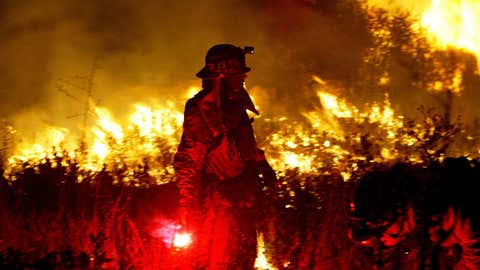 A Los Angeles County firefighter uses a flare to light a backfire to try and save a condominium complex from an out-of-control wildfire, October 27, 2003, in Chatsworth, Calif. (Justin Sullivan/Getty Images)