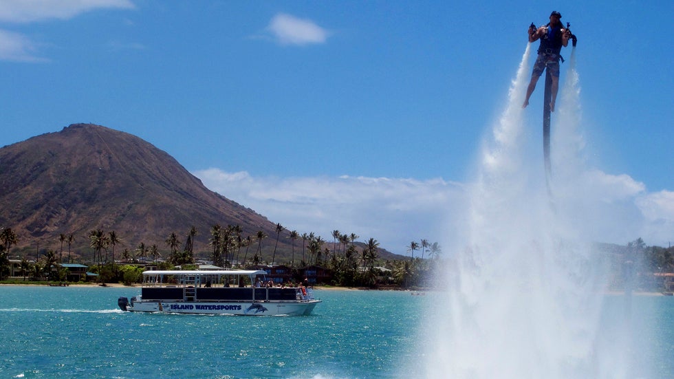 A jetpack instructor at H2O Water Sports Powered by Seabreeze demonstrates how to use a Jetlev in Honolulu, July 19, 2013. Thrill-seekers are eager to try the next new watersport, but Hawaii state officials are questioning their safety and how they may affect fish, coral and other natural resources in the islands. (AP Photo/Audrey McAvoy)