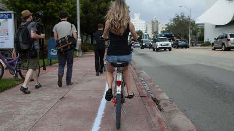 A woman rides a bike along the chalk outline showing how far inland 3 feet of sea level rise would reach in Miami Beach, Fla. (Courtesy Jayme Gershen/High Water Line)