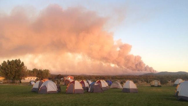 A smoke column rises near a camp site in eastern Arizona as the San Juan fire continues to rage, Sunday, June 29, 2014. (Facebook/San Juan Fire Information)