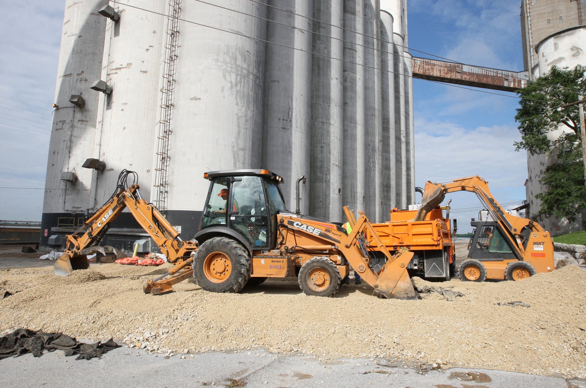 The Illinois Department of Transportation work Monday June 10, 2013 to begin removing the rock road that crossed East Broadway at Williams Street in Alton, Ill. The road allowed access to the ConAgra Mill during flooding. (AP Photo/The Telegraph, John Badman)