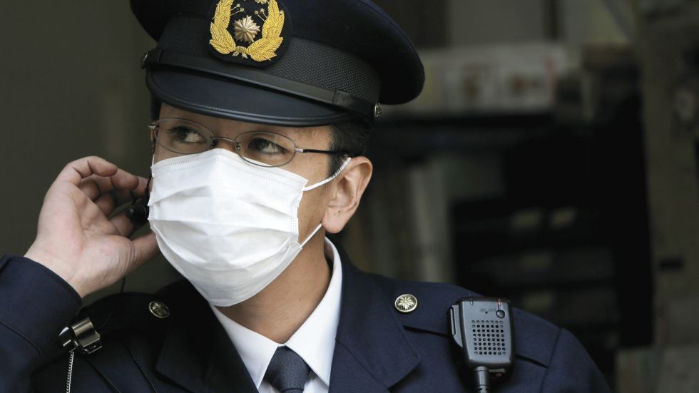 In this photo taken March 16, 2013, a police officer wearing a mask is on duty at a police station in Tokyo. Japan is becoming a sea of surgical masks. It&rsquo;s about pollen, about germs and even a little about China, its polluting rival across the sea. (AP Photo/Itsuo Inouye)