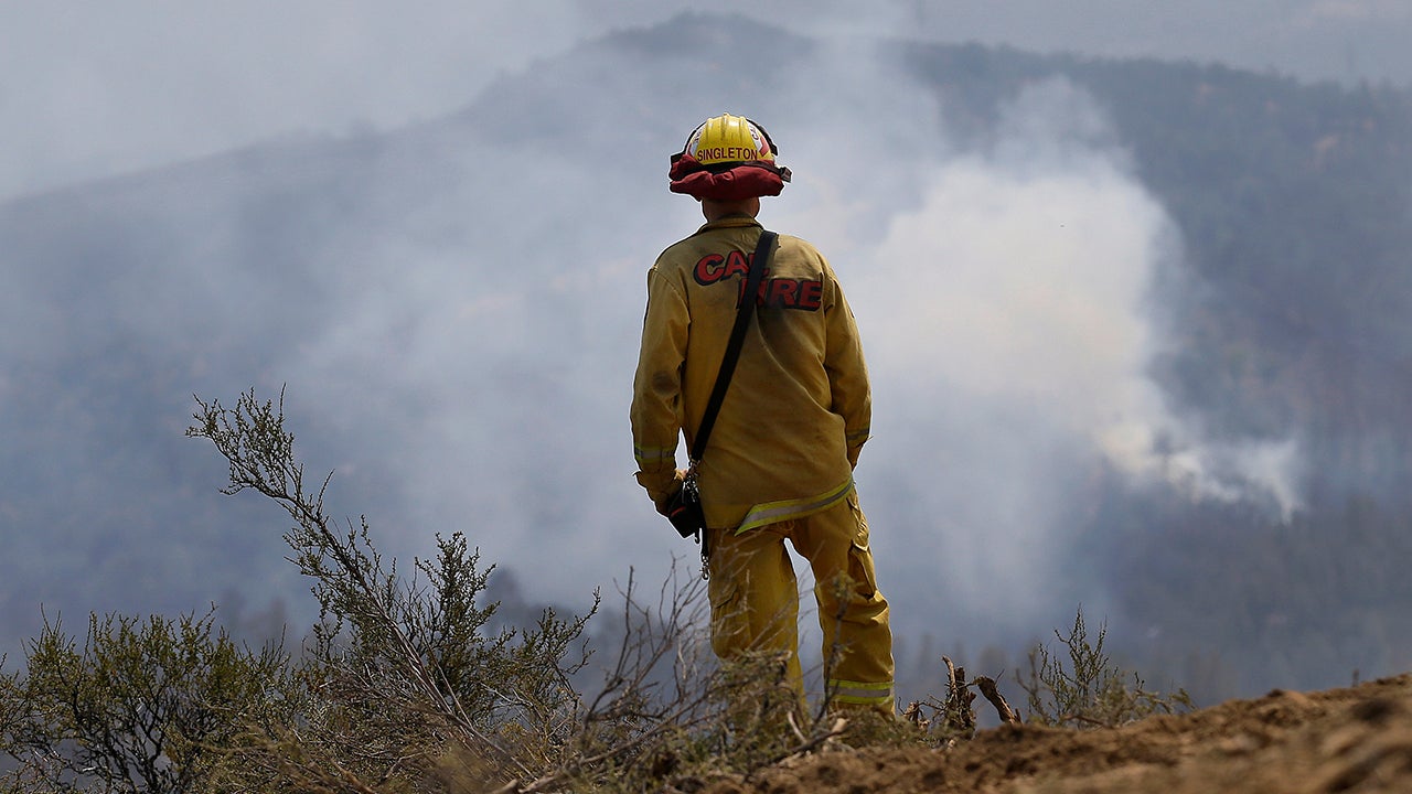 Cal Fire engineer Clint Singleton looks out at a plume of smoke near Clearlake, Calif., Wednesday, Aug. 5, 2015. Thousands of firefighters battling an unruly Northern California wildfire were aided overnight by cooler temperatures and higher humidity, but the fire is still less than a quarter contained. (AP Photo/Jeff Chiu)