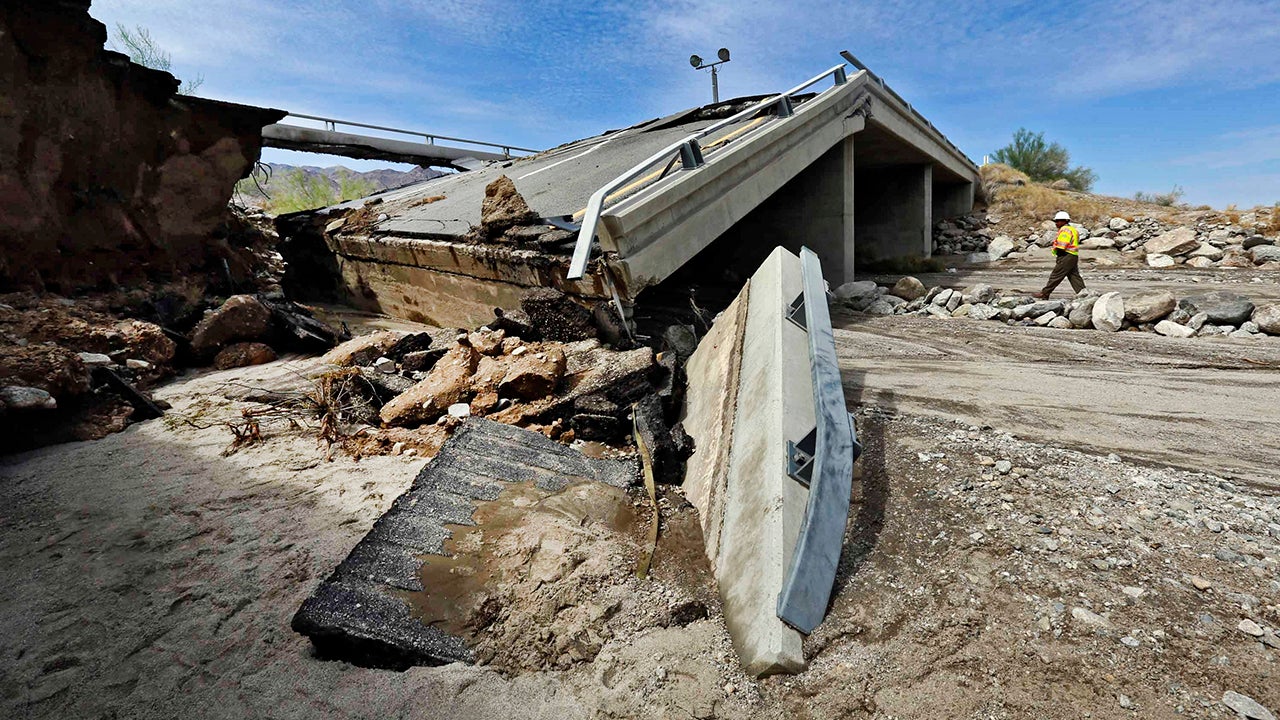 A worker walks near a washed-out bridge near the town of Desert Center, along Interstate 10 in Southern California, on Monday, July 20, 2015. All traffic along one of the major highways connecting California and Arizona was blocked indefinitely when the bridge over a desert wash collapsed during a major storm, and the roadway in the opposite direction sustained severe damage. (AP Photo/Nick Ut)