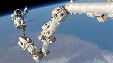 International Space Station’s Canadarm2 is used to help astronaut Steve Robinson during the mission’s third session of extravehicular activity on Aug. 3, 2005. (NASA)