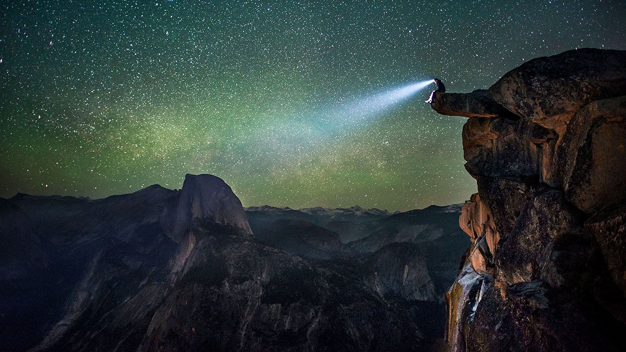 An unknown man in a head lamp on the edge of Glacier Point in Yosemite stares at the incredible view. (Christian Adam/Caters)