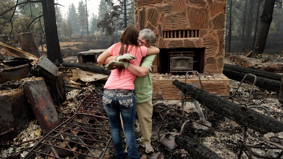 Donna Garner, right, embraces former employee Napua Gonsales-Merck while they sift through the remains of the Fireside Village, a restaurant and shop owned by the Garners for over 30 years, in the aftermath of the Eiler Fire in Hat Creek, Calif. (AP Photo/Marcio Jose Sanchez)