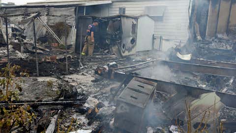 A Napa firefighter inspects one of four mobile homes that were destroyed in a gas fire Sunday, Aug. 24, 2014, at the Napa Valley Mobile Home Park, in Napa, Calif after a preliminary 6.0-magnitude earthquake struck the San Francisco Bay area. (AP Photo/Ben Margot)