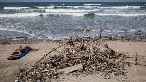 A tourist sunbathes beside debris at Kuta Beach on January 17, 2014 in Kuta, Indonesia. The sight of trash Kuta beach, one of Bali's most popular tourist destinations, has become an annual phenomenon as debris are carried to the beach by strong currents during the winter months. (Agung Parameswara/Getty Images)