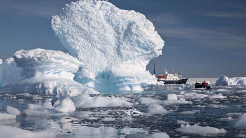 An inflatable boat carries tourists past an iceberg along the Antarctic Peninsula. In a remote, frozen, almost pristine land where the only human residents are involved in research, tourism comes with risks, for both the continent and the tourists. (AP Photo/Aurora Expeditions, Andrew Halsall)