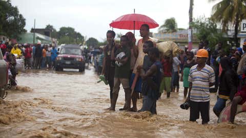 People stand in a street flooded by a nearby river overflowing from the heavy rains caused by Hurricane Matthew, in Leogane, Haiti, Wednesday, Oct. 5, 2016.