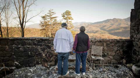 Richard T. Ramsey and Sue Ramsey hold hands while looking at the skyline from the remains of their house of 41 years, Thursday, Dec. 1, 2016, in Gatlinburg, Tennessee. They safely evacuated from their home as wildfire approached Monday evening. (Andrew Nelles/The Tennessean via AP)