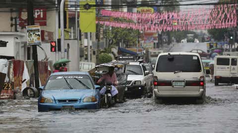 Vehicles navigate a flood-prone area caused by rains from Typhoon Nock-Ten in Quezon city, north of Manila, Philippines on Monday, Dec. 26, 2016. The powerful typhoon slammed into the eastern Philippines on Christmas Day, spoiling the biggest holiday in Asia's largest Catholic nation, where a governor offered roast pig to entice villagers to abandon family celebrations for emergency shelters. (AP Photo/Aaron Favila)