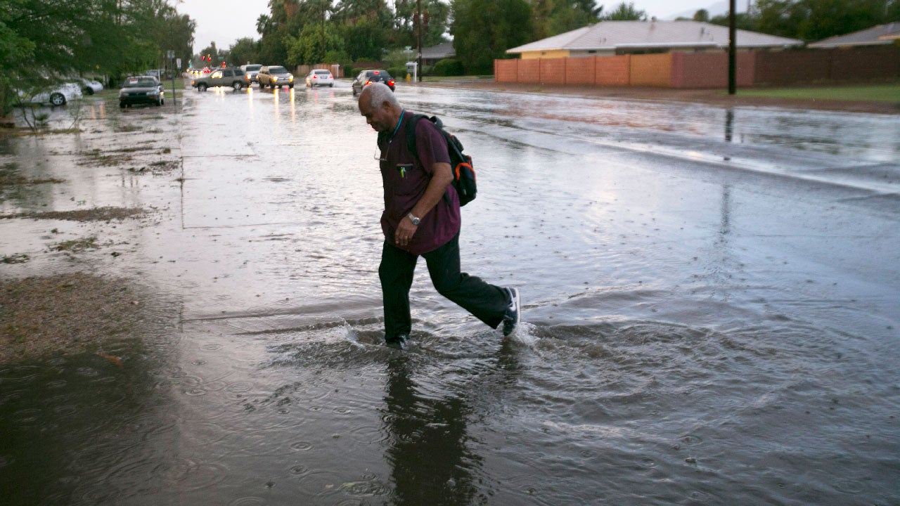 Percy Proffitt crosses a flooded 40th Street south of Thomas Road in Phoenix following heavy rains on Monday evening, July 18, 2016. (David Wallace/The Arizona Republic via AP)