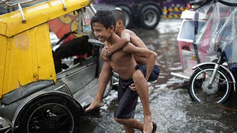 Filipino boys play along a flooded street caused by heavy rains from Typhoon Melor in suburban Navotas, north of Manila, Philippines on Wednesday, Dec. 16, 2015. Typhoon Melor left at least one person dead and wide areas without power Tuesday as it crossed over the central Philippines. (AP Photo/Aaron Favila)