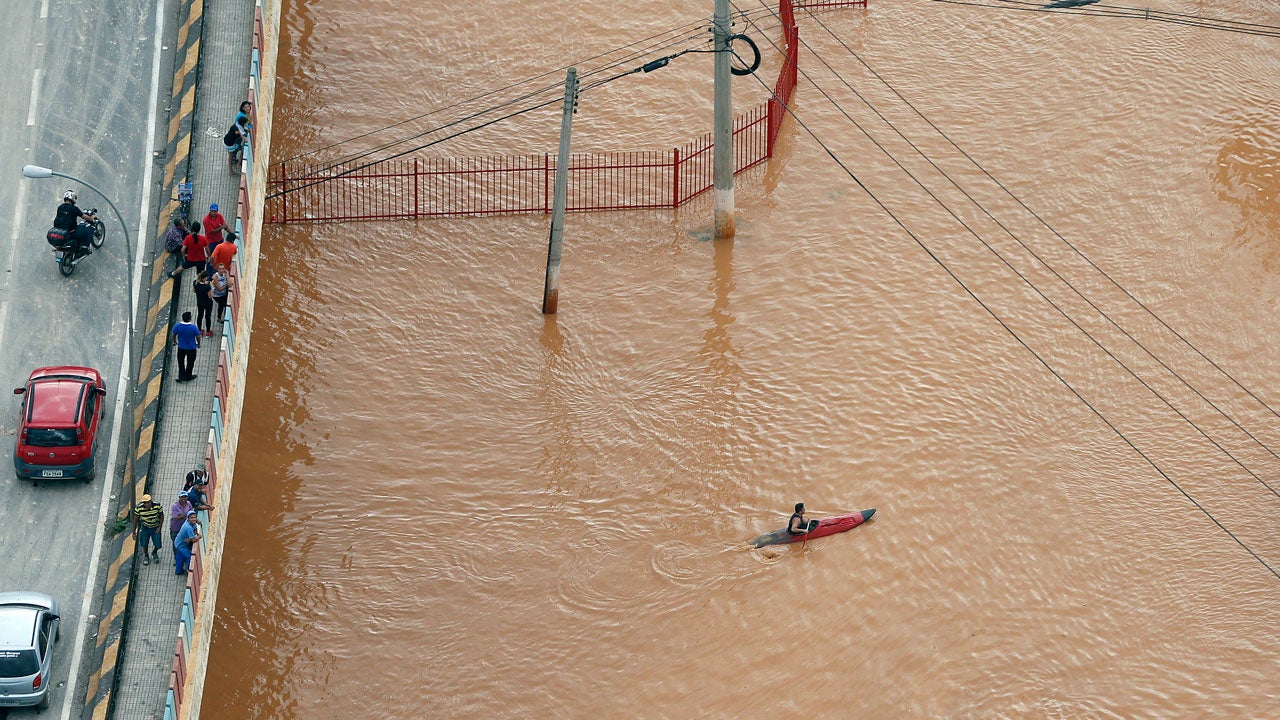 In this aerial photo, a man maneuvers a kayak through flood water in Franco da Rocha, in the greater Sao Paulo area, Brazil, Friday, March 11, 2016. (AP Photo/Andre Penner)