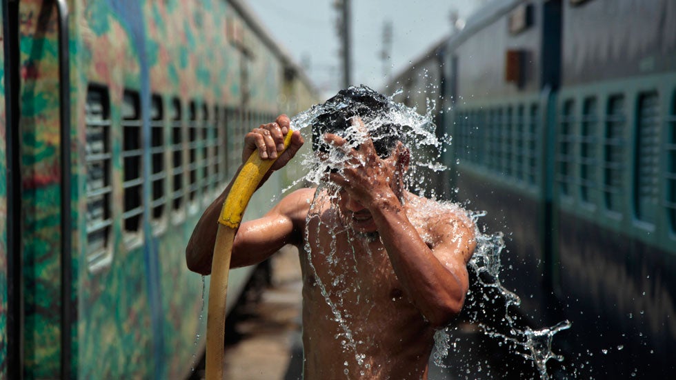 A man douses himself in water at a railway station to cool himself down in Jammu, India, Monday, June 9, 2014. (AP Photo/Channi Anand)