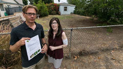 Michael Korte and his wife Laura Whitney, pose outside their home lawn in Glendora, Calif., Thursday, July 17, 2014. (AP Photo/Damian Dovarganes)