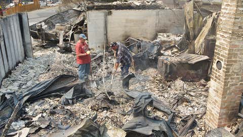 Randy Loucks, right, of Brewster, Washington and Rich Pitkethly of Brewster dig through the remains of a home belonging to Loucks mother-in-law following a wildfire. (Photo: Getty/Stephen Brashear)