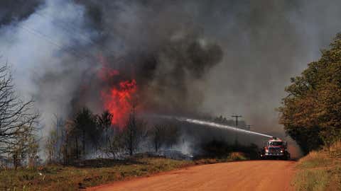 Firefighters work to extinguish a flare-up on Monday, May 5, 2014, in Guthrie, Okla. (AP Photo/Nick Oxford)