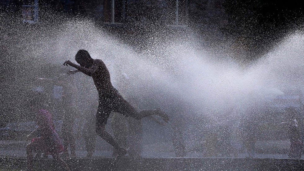 Kids cool off in the spray of an open hydrant on a hot evening in Lawrence, Mass. on July 16, 2013. (AP Photo/Elise Amendola)