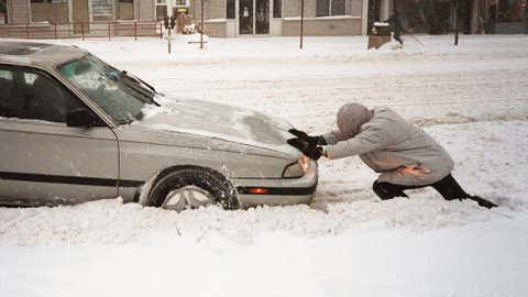 An unidentified man pushes a car out of the snow January 7, 1996 in Washington, D.C. Image credit: BOB PEARSON/AFP/Getty Images