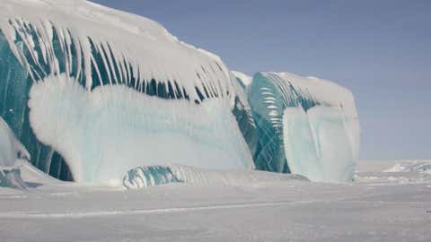 Though they appear to be frozen ocean waves, these blue ice towers in Antarctica are created when ice compresses, forcing trapped air bubbles out. When sunlight passes through this thick frozen ice, blue light waves are visible but the red light is absorbed. (Photo credit: Tony Travouillon)