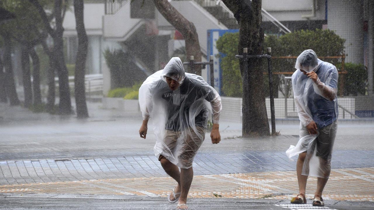 Passersby make their way through strong wind caused by approaching typhoon Vongfong in Naha, Okinawa, southern Japan, Saturday, Oct. 11, 2014.  (AP Photo/Kyodo News)
