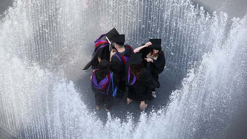 Graduates celebrate after leaving their graduation ceremony at the Royal Festival Hall by entering the fountain 'Appearing Rooms', by Danish artist Jeppe Hein, on the Southbank in high temperatures on July 18, 2013 in London, England. (Oli Scarff/Getty Images)