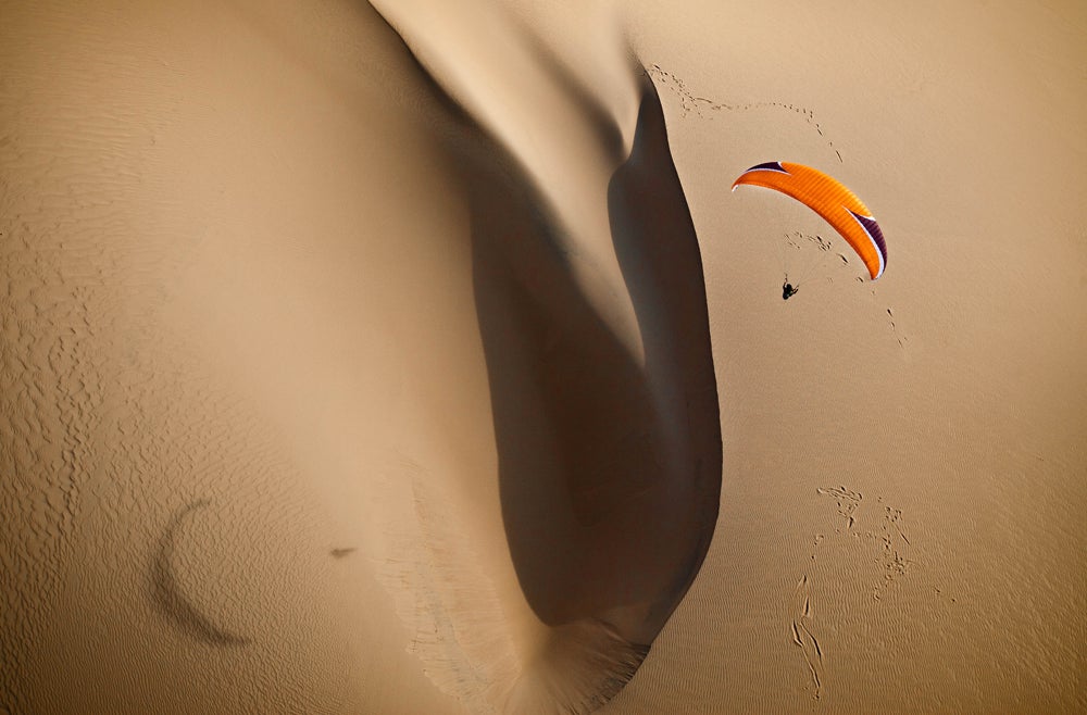 A gorgeous shot of a paraglider flying over the large sand dune in the Bazaruto Archipelago in Africa. (Image: Jody MacDonald)