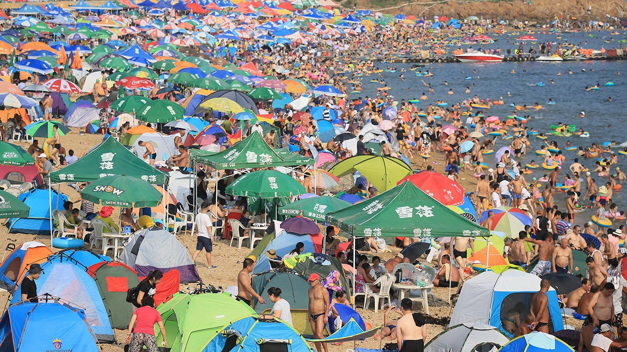 People enjoy themselves at a beach to beat the heat as the temperature reaches 31 degrees on July 31, 2016 in Dalian, China.  (VCG/VCG via Getty Images)