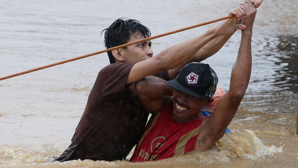 A rescuer helps a resident to go to a safer area after heavy rains spawned by Tropical Storm Fung-Wong flooded Marikina city, east of Manila, Philippines and most parts of the metropolis Friday, Sept. 19, 2014. (AP Photo/Bullit Marquez)