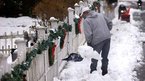 Steve Roche shovels snow as neighbors use snow blowers to clear the sidewalk, Dec. 15, 2013, in Walpole, Mass. (AP Photo/Steven Senne)