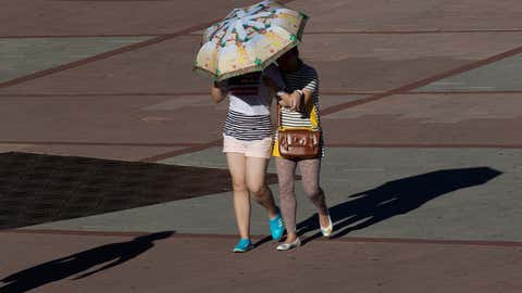 Two women protect themselves from the sun with a sun umbrella in Madrid, Spain Sunday Aug. 4, 2013. Madrid is having a mini-heat wave this week as temperatures reach up to 39 degrees Celsius (102 Fahrenheit). (AP Photo/Paul White)