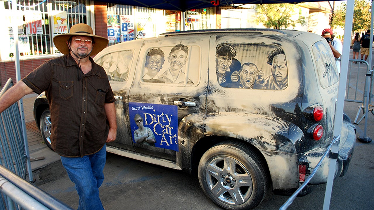 Scott Wade stands with one of his signature dirty cars, displaying a scene from The Three Stooges. (&copy;2014 Scott Wade&rsquo;s Dirty Car Art)