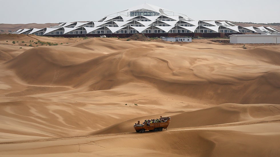 Tourists ride past the Desert Lotus Hotel under construction in Xiangshawan Desert, also called Sounding Sand Desert on July 17, 2013, in Ordos of Inner Mongolia Autonomous Region, China. (Feng Li/Getty Images)