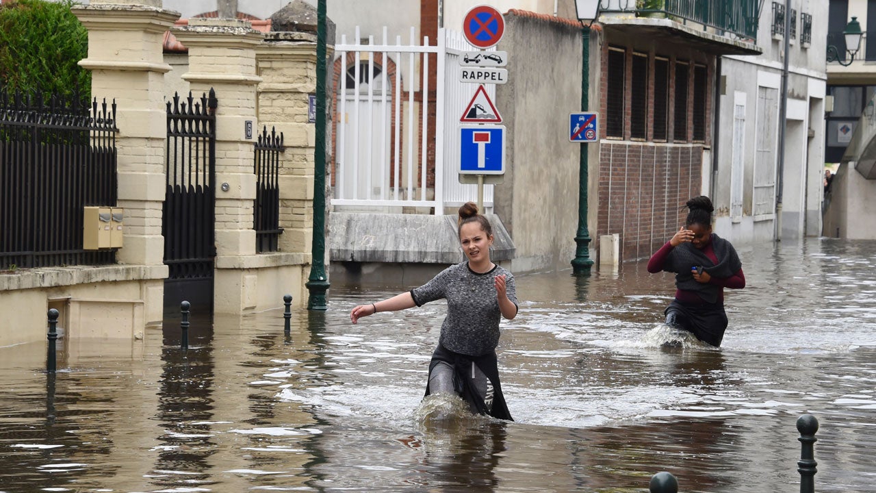 Two women walk through flooded streets of Montargis, France, south of Paris, on June 1, 2016. Torrential downpours lashed parts of northern Europe, leaving four dead in Germany, breaching the banks of the Seine in Paris and flooding rural roads and villages. 