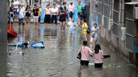 This photo taken on July 21, 2016, shows people making their way through a flooded area in Changping District in Beijing, China.